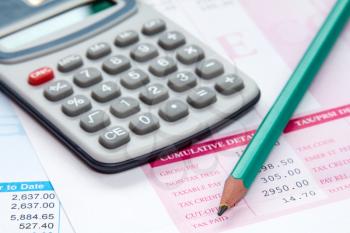 Calculator and pencil on the statement of payroll details