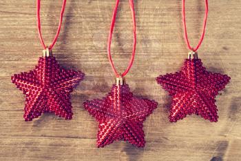 Three Christmas stars hanging on a wooden background