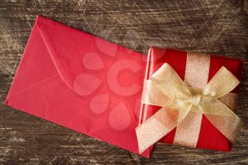 Gift box and red envelope on wood background