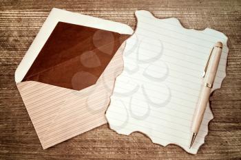Open envelope with blank burned letter on wooden background