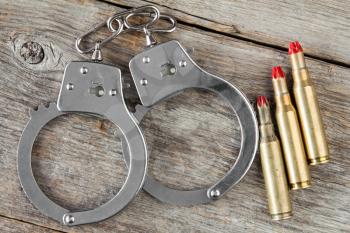 Dummy cartridges and handcuffs on the wooden background