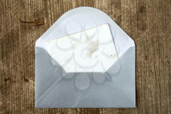 Open silver envelope with blank card on wooden background