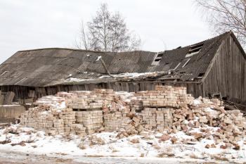 Pile of masonry bricks against abandoned and damaged building
