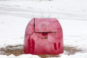 Broken red container for grit and salt in winter time