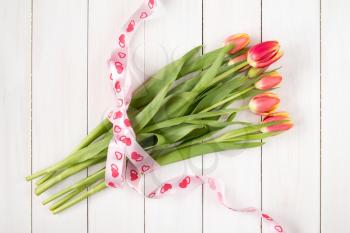 Tulips bouquet with ribbon on white wooden background
