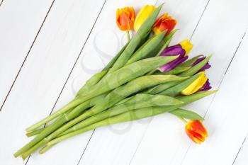 Bouquet of colorful tulips lying on white wooden background. Top view.