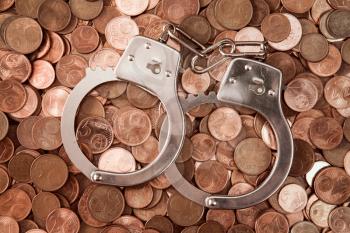 Handcuffs and pile of coins as security concept