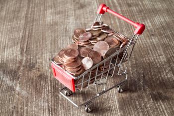 Shopping cart with Euro cent coins on wooden background