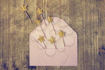 Open pink envelope with golden stars on sticks