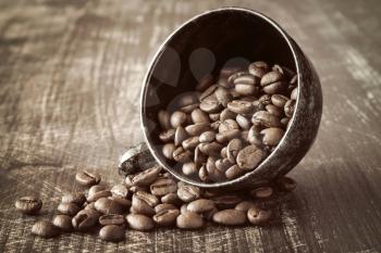 Black coffee cup and coffee beans on old wooden background.