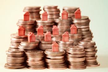 Plastic houses resting on copper coins stacks. Concept for property ladder, mortgage and real estate investment