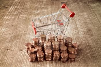 Shopping cart with Euro cent coins on wooden background. Retail,sale or marketing concept