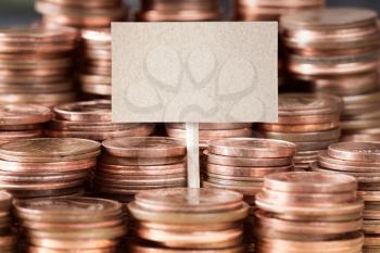 Blank sign with stacks of copper coins (Euro cents)