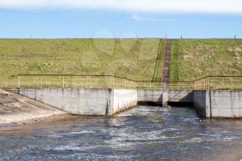 Water flowing over floodgates of a small dam in a springtime