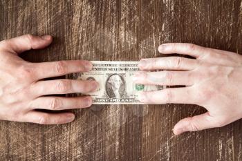 Hands pulling dollar banknote.Concept for business rivalry.