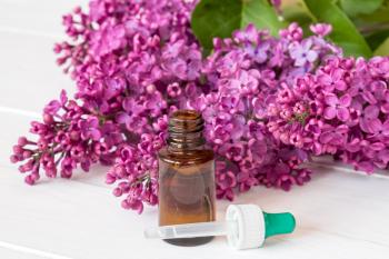 Bottle with aroma oil and lilac flowers  on white background