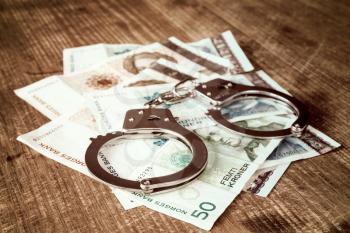 Norwegian kroner banknotes and metal handcuffs. Concept For Corruption or Fraud