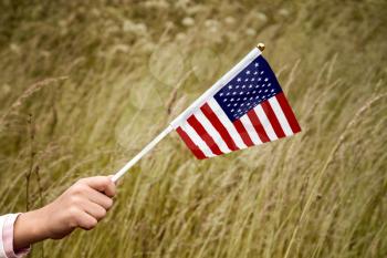 Child holding small US flag on the wind outdoor