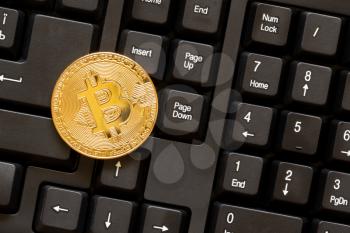 One golden BTC coin on computer keyboard.Top view.