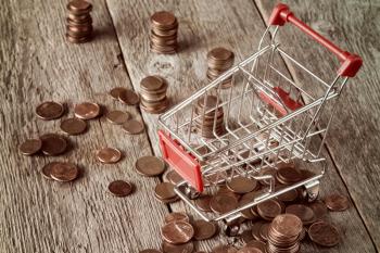Shopping cart with coins on wooden background. Retail,sale or marketing concept