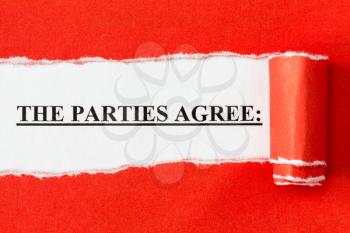 The phrase THE PARTIES AGREE appearing behind torn paper. Agreement,contract or deal concept.