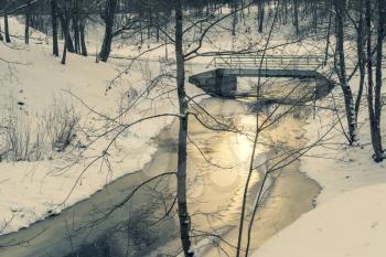 Winter scene at the park, small bridge over frozen water in the morning