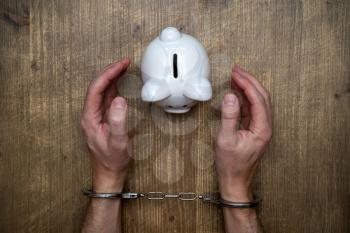 Handcuffed hands and piggy bank. Concept stealing savings from piggy-bank