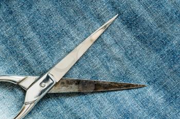 Metal scissors laying on the blue jeans background