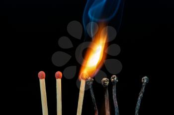 Line of burning matches on dark background