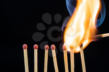 Line of burning matches on black background