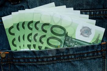 Banknotes  of Euro currency sticking out of the blue denim jeans pocket. Money in jeans pocket for travel and shopping.