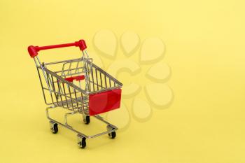 Small shopping cart on yellow background. Purchase or marketing concept