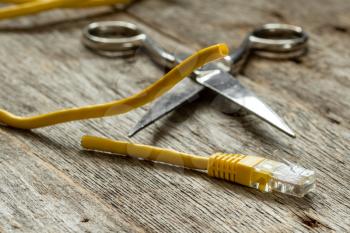 Network cable and scissors on wooden background
