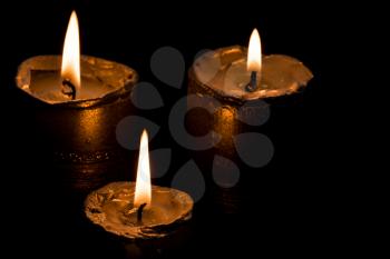 Three candles burning on a dark background