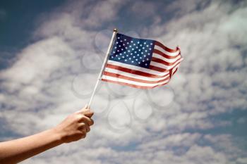 Child  waving US flag on the sky background