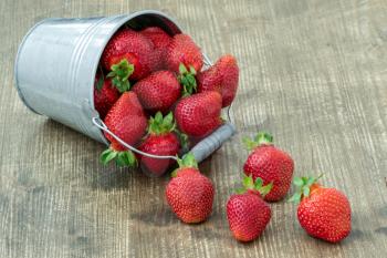 Small bucket with delicious fresh strawberries on wooden table