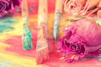 Abstract painting with dry roses and paint brushes