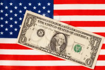 One Dollar bill over the flag of the United States