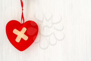 Heart with plaster hanging on white wooden background.The concept of divorce, separation, quarrel