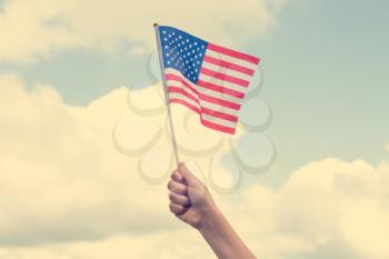 Child holding small US flag on the sky background