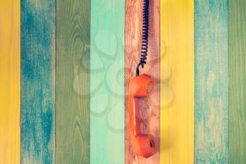 Hanging the phone handset on the color wooden wall background