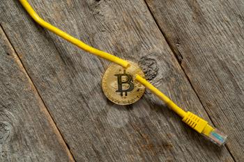 Gold bitcoin coin and damaged network cable.Concept of a cryptocurrency market crisis