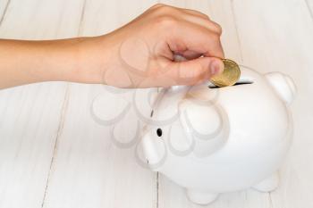 Child's hand putting a coin into piggy bank,a saving money for future education concept