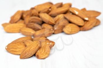 Pile of almonds seeds  on white wooden background