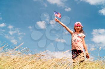 Cute smiling little girl  holding an american flag on sunny day. Independence Day, Flag Day concept