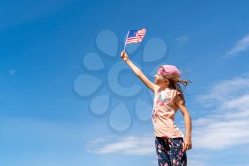 Cute girl  holding an american flag on sunny day. Independence Day, Flag Day concept