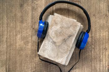 Audio book concept. Headphones and book over wooden table. Top view with space for your text