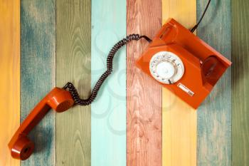 Orange retro  telephone on colorful wooden background. Top view.