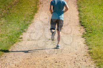 Rear view of man jogging on the rural road. Fitness, sport and healthy lifestyle concept