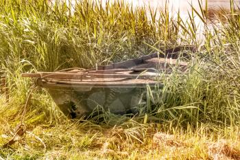 Old wooden rowboat on the lake bank in summer season